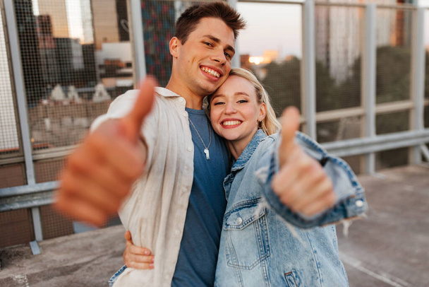 happy young couple showing thumbs up on roof top - Foto, Imagem