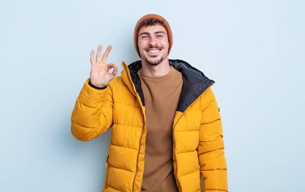 young handsome man feeling happy, showing approval with okay gesture. winter concept - Fotoğraf, Görsel