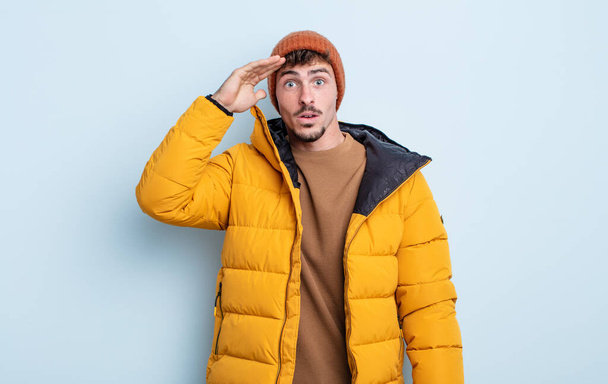 young handsome man looking happy, astonished and surprised. winter concept - Foto, Bild