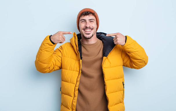 young handsome man smiling confidently pointing to own broad smile. winter concept - Fotoğraf, Görsel