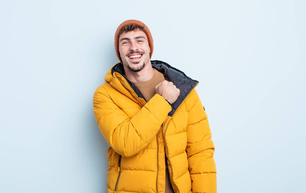 young handsome man feeling happy and facing a challenge or celebrating. winter concept - Photo, Image