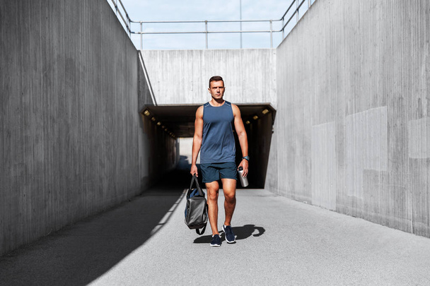 sportsman with bag and bottle walking outdoors - Фото, зображення
