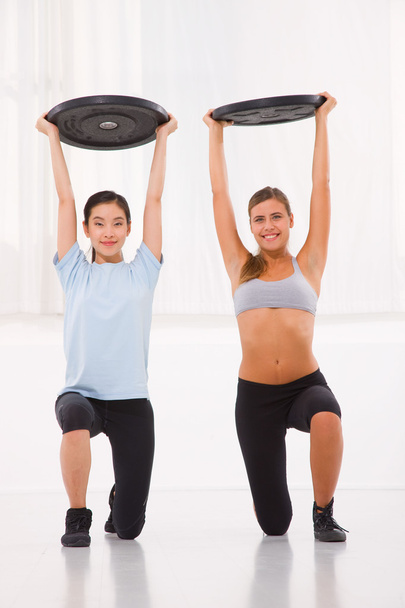 Dos mujeres jóvenes levantando peso en el gimnasio
 - Foto, imagen