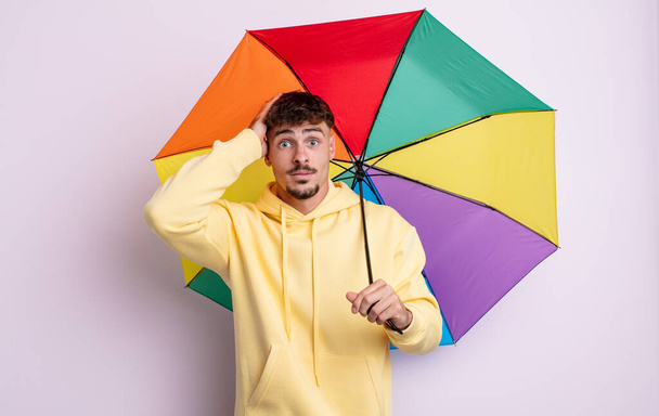 young handsome man feeling stressed, anxious or scared, with hands on head. umbrella concept - Φωτογραφία, εικόνα