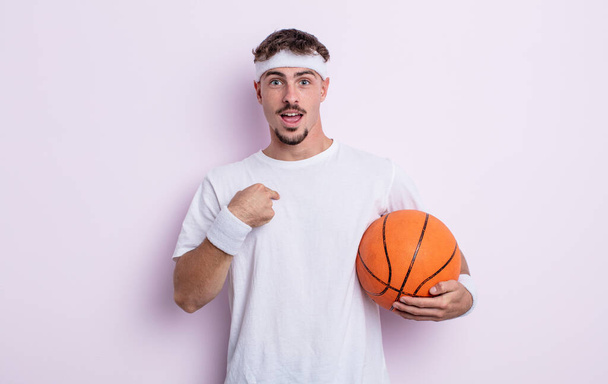 young handsome man feeling happy and pointing to self with an excited. basketball concept - 写真・画像