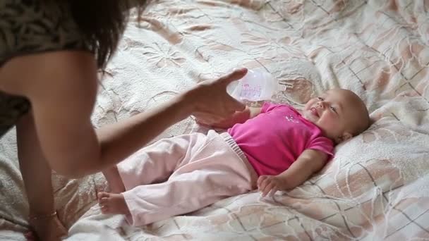 小さな赤ちゃんのベッドに横になっていると、ボトルからミルクを飲む - 映像、動画