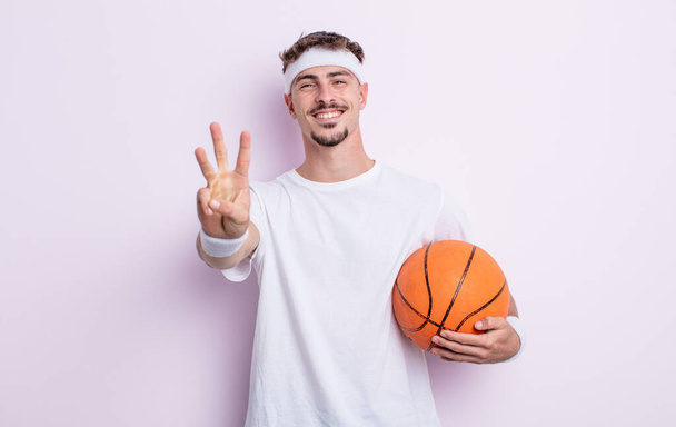 jovem bonito homem sorrindo e olhando amigável, mostrando número três. conceito de basquete - Foto, Imagem