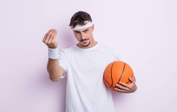 Молодой красивый мужчина делает капис или денежный жест, приказывая тебе заплатить. баскетбол - Фото, изображение