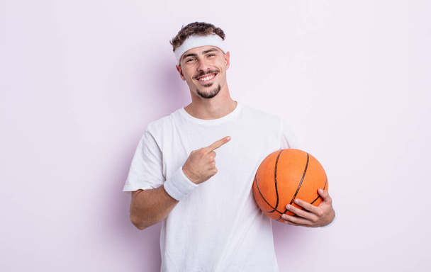young handsome man looking excited and surprised pointing to the side. basketball concept - Фото, изображение
