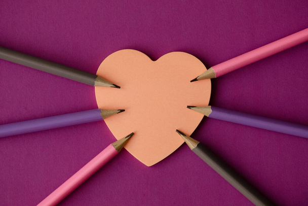 Simple pencils on paper with note in the form of a pink heart on a lilac background. Valentine's day concept - Foto, Imagem