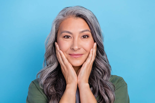 Photo of nice aged grey hairdo lady hands face wear khaki shirt isolated on blue color background. - 写真・画像