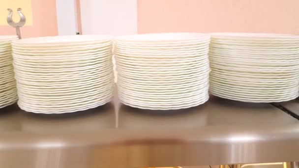 Vidéo 4k, mouvement lent de la caméra le long de plaques vides blanches propres empilées. Les assiettes sont sur un stand buffet, le concept de la nourriture dans le café de l'hôtel - Séquence, vidéo
