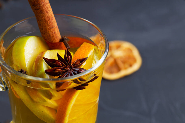 close-up mulled wine with spices.Christmas hot white mulled wine in glass with orange, honey, cinnamon sticks and star anise with spices on black background. Spicy warm beverage. copy space - Fotoğraf, Görsel