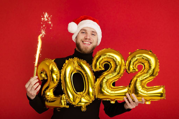 サンタクロースの帽子の男は番号2022と輝きを保持しています - 写真・画像