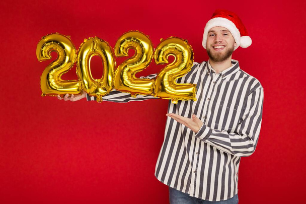 Człowiek w świątecznym kapeluszu trzyma numery 2022. Wkrótce nadejdzie Nowy Rok. - Zdjęcie, obraz