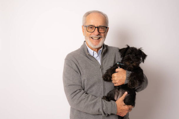 Senior sorrindo homem abraçando seu cachorro schnauzer isolado sobre fundo branco. - Foto, Imagem