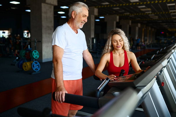 Old man on treadmill, female personal trainer - Φωτογραφία, εικόνα