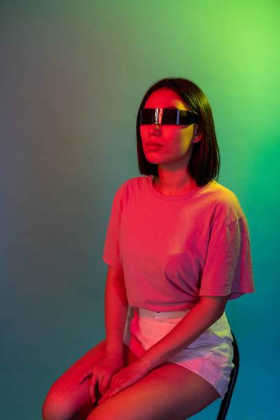 Молодая азиатская разнообразная женщина в умных научно-фантастических очках, изолированных на красочном фоне  - Фото, изображение