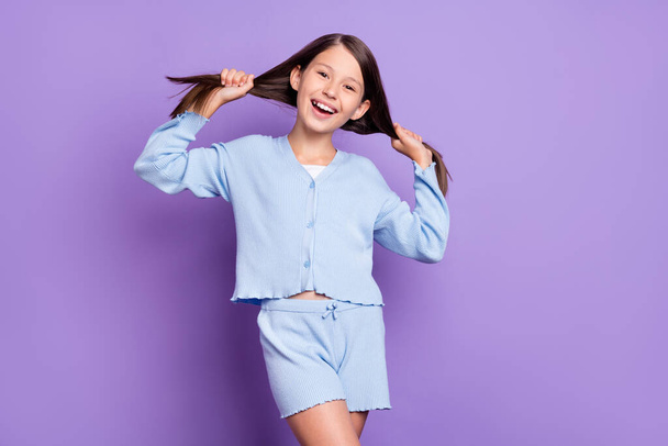 Foto di cool bruna bambina mani capelli indossare pantaloncini camicia blu isolato su sfondo di colore viola - Foto, immagini