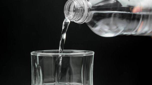 Μπουκάλι νερό χύνεται σε ένα ποτήρι - Φωτογραφία, εικόνα
