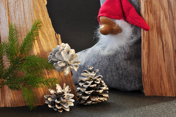 Χριστουγεννιάτικα στολίδια, ένα ξωτικό και ασημένια κουκουνάρια, κλαδί πράσινου χριστουγεννιάτικου δέντρου σε ξύλινο πλαίσιο - Φωτογραφία, εικόνα
