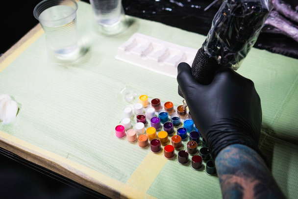 Close-up de tatuagem artista local de trabalho peças e pintura, máquinas e outros equipamentos. Tatuagem profissional trabalhando tatuagem em estúdio - Foto, Imagem