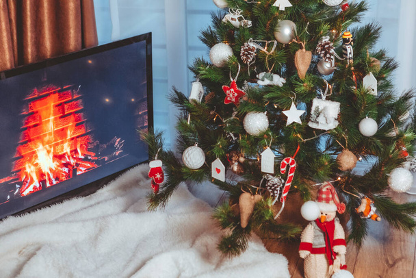 Lviv, Ουκρανία - 15 Δεκεμβρίου 2021: Θέα στο τζάκι στην οθόνη. τηλεόραση κοντά στο χριστουγεννιάτικο δέντρο αντίγραφο χώρο - Φωτογραφία, εικόνα