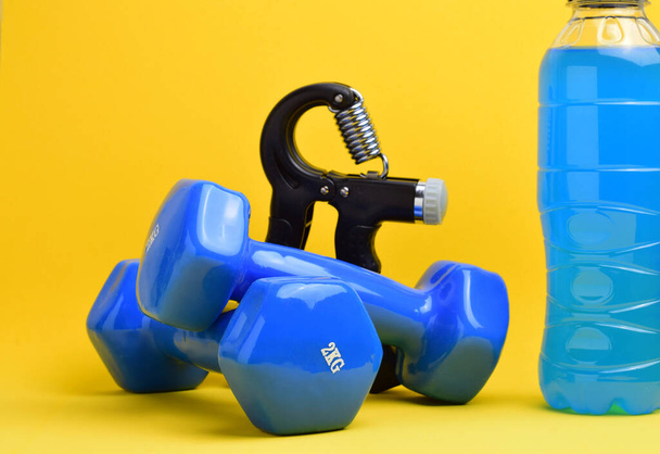 Hand grip fitness training, dumbbells and various accessories, on a yellow background. Copy space. - Photo, Image