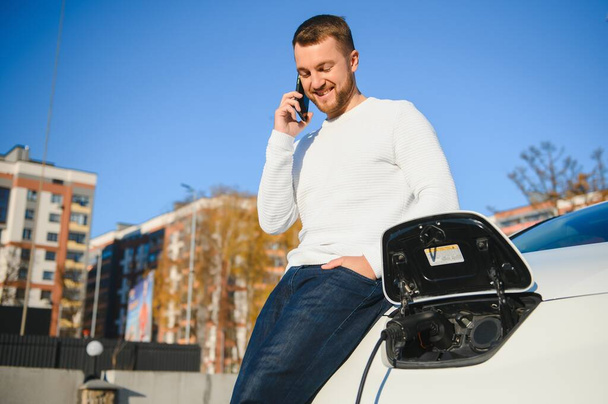 Man charges an electric car at the charging station - Foto, immagini