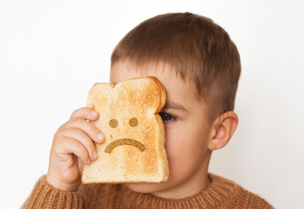Children and gluten. Preschool boy with toasted bread, with sad emoji. Gluten intolerance by kids. - Photo, Image