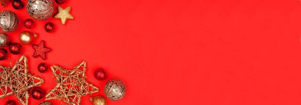 Χριστουγεννιάτικα σύνορα με κόκκινα και χρυσά στολίδια. Πάνω από την προβολή σε ένα κόκκινο φόντο banner χαρτί. Αντιγραφή χώρου. - Φωτογραφία, εικόνα