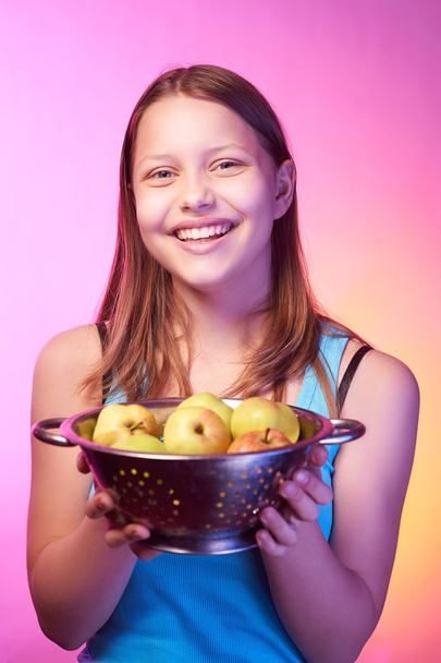 Teen girl holding a colander full of apples - Foto, afbeelding