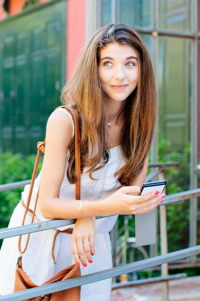 Happy and dreamy girl using her mobile phone - Photo, Image