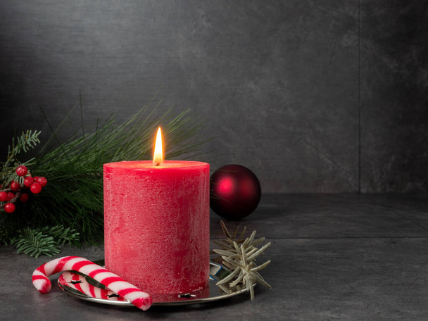 Red Christmas candle and Christmas decorations on a gray background. - Photo, image