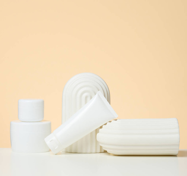 valkoinen muovisäiliö kosmetiikkaa varten valkoisella pöydällä. Purkki ja tuuba, tuotteiden esittely ja myynninedistäminen - Valokuva, kuva