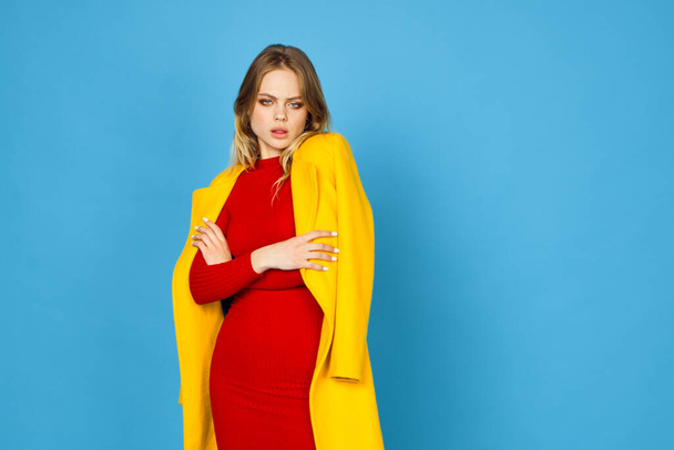 woman in yellow jacket posing makeup fashion blue background - Foto, afbeelding