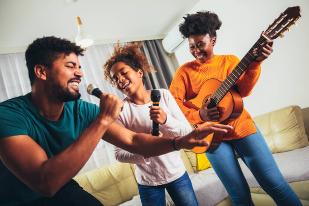 Daughter with her parents singing a favorite song on a karaoke microphone - Foto, afbeelding