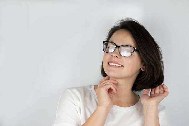 Studiofoto eines jungen schönen lächelnden Mädchens mit Brille und T-Shirt auf weißem Hintergrund - Foto, Bild