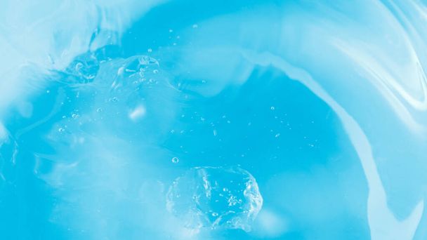 Blurred blue fresh water with falling ice piece as background with copy space - Foto, imagen