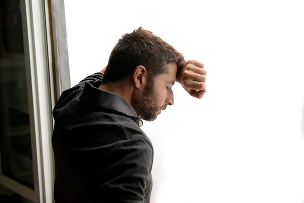 Привлекательный человек опираясь на окно страдает эмоциональным кризисом и депрессией
 - Фото, изображение