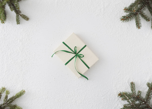 Homemade gift with bow white background and conifer brunches in corners flat lay do it yourself on snow - Photo, Image