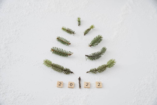 Arbre de Noël fait maison avec fond blanc et brunchs de conifères dans copyspace plat lay le faire vous-même minimalisme sur la neige avec 2022 nouveaux cubes de l'année - Photo, image