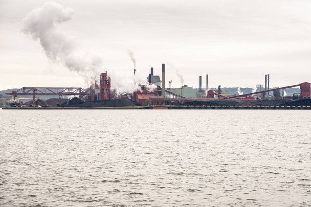 Vista de un molino de acero frente al mar en un día nublado de otoño. Hamilton, ON, Canadá. - Foto, imagen