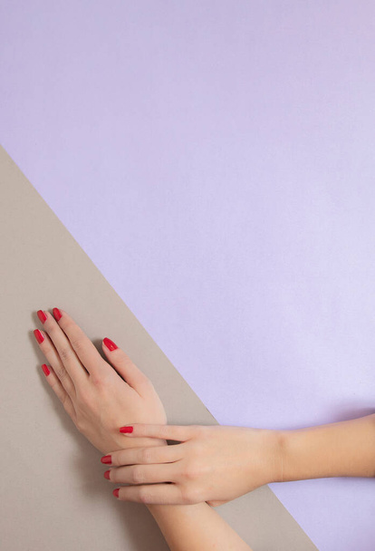 Красивые женские руки с лаком для ногтей, на фиолетовом и сером фоне - Фото, изображение