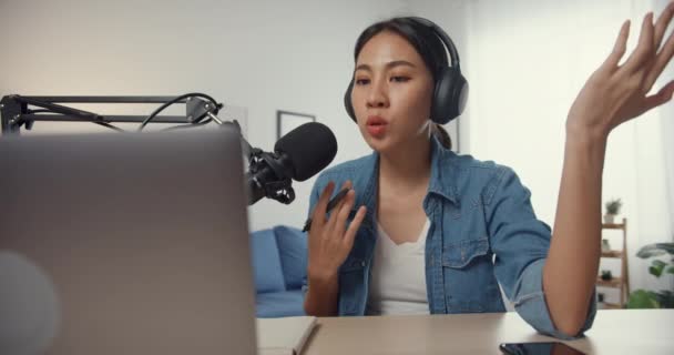 Ευτυχισμένη Ασία κορίτσι καταγράφει ένα podcast σε φορητό υπολογιστή με ακουστικά και μικρόφωνο μιλάμε με το κοινό στο σαλόνι. Γυναικείο podcaster κάνει podcast ήχου από το στούντιο του σπιτιού της. Μείνετε στο σπίτι έννοια. - Πλάνα, βίντεο