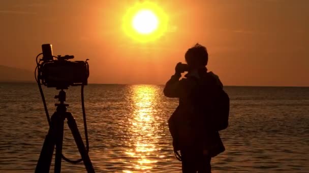 Fotograf przyrody fotografowania żółty ocean zachód słońca na plaży sylwetka za kulisami - Materiał filmowy, wideo