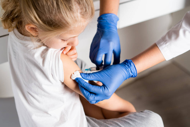 szczepienia dzieci, dziewczynka na wizytę lekarską, zastrzyk w ramię, conce - Zdjęcie, obraz