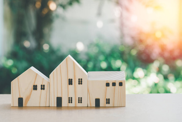 Eco home concept. Klein houten huis model met groene natuurlijke bokeh achtergrond met kopieerruimte. - Foto, afbeelding