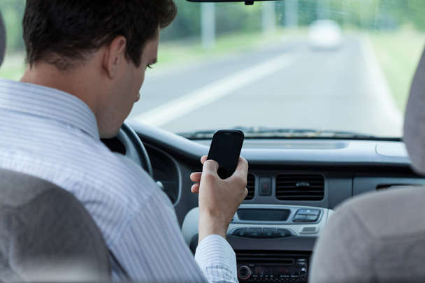 Man texting on mobile phone during driving a car - Foto, afbeelding