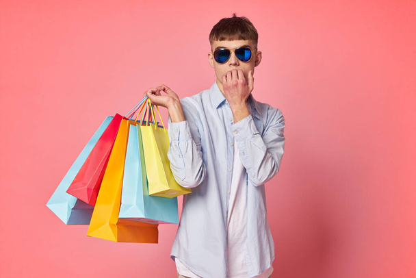 guy in sunglasses with shopping bags pink background - Foto, Imagem